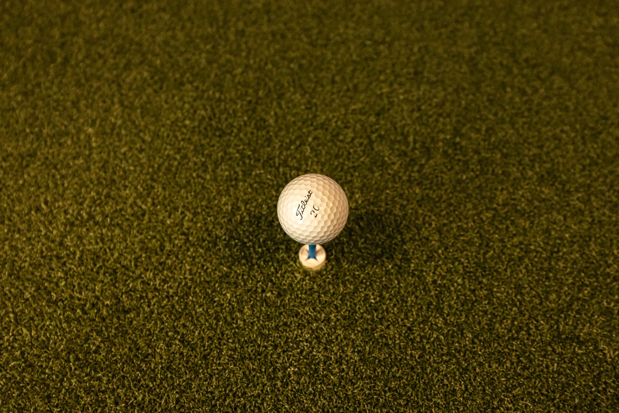 A golf ball on a tee on the hitting turf.